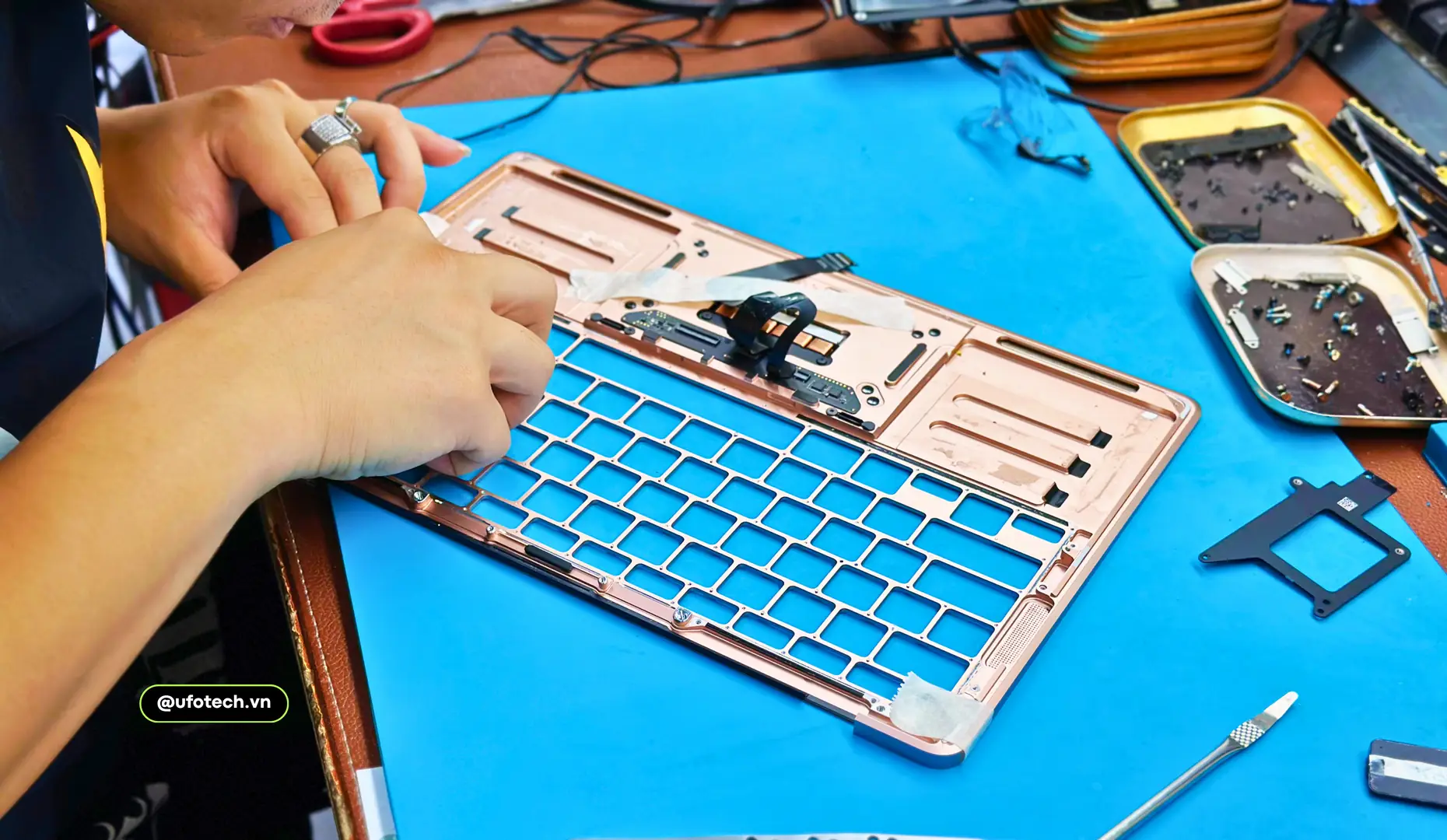 Kỹ thuật viên tại UFOTECH đang tiến hành bóc tách và thay thế bàn phím MacBook bị lỗi chập mạch.